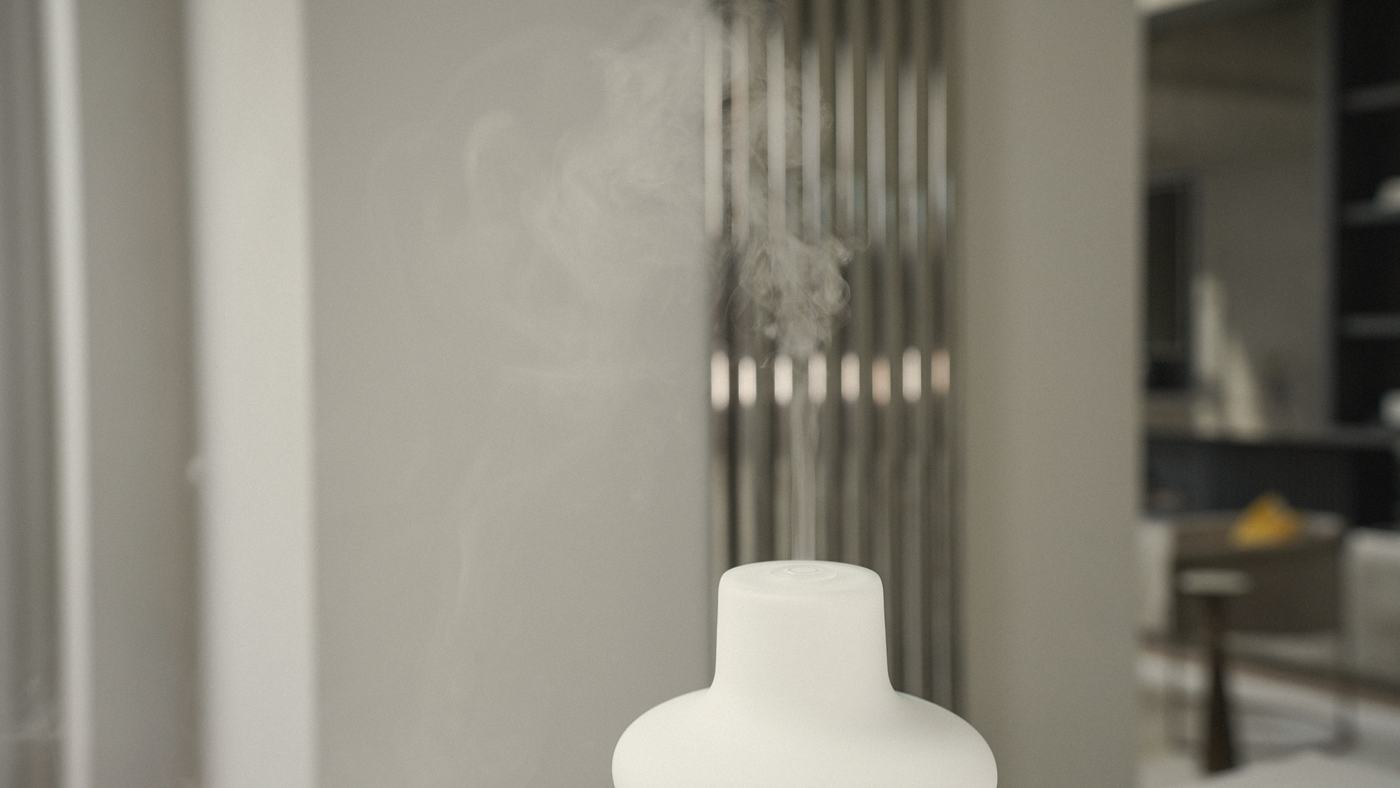A fine ribbon of mist rising from the white glass diffuser in a softly lit room